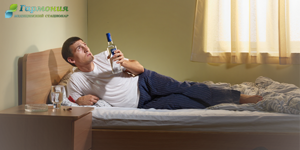 Мужчина лежит на кровати с бутылкой